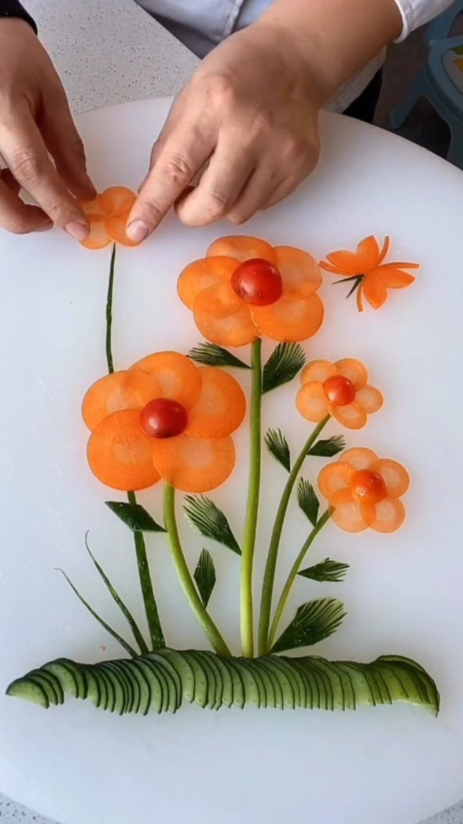 a person is making an art project with flowers on a white plate and green leaves