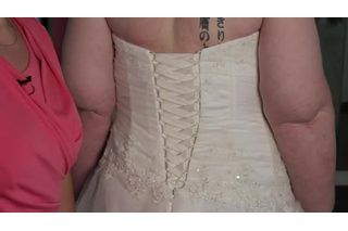 the back of a bride's wedding dress with tattoos on her neck and shoulder