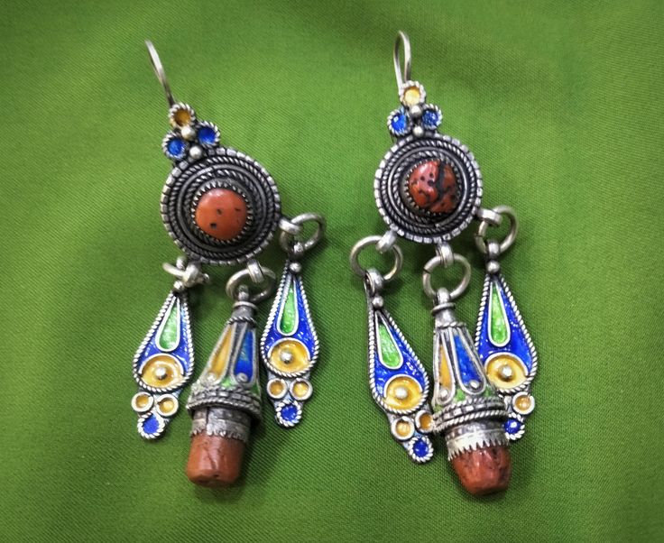 Magnificent Kabyle earrings in enameled sterling silver with blue, green and yellow colors, inlaid with two real coral cabochons. ✓ Height: 8 cm. ✓ Width: 3 cm. ✓ Material: 925 sterling silver, real coral. ✓ Weight: 29.6 grams. ✓ Origin: Greater Kabyle region 1960s - Algeria. ✓ Shipping will always be via DHL for free. ✓ Shipping to USA 3-7 business days. ✓ Shipping to Europe 3-5 working days. I have been working in the field of crafts for 30 years and for the first time I am selling on websites Traditional Hallmarked Enamel Jewelry, Enamel Pendant Earrings For Gifts, Turquoise Dangle Jewelry For Festivals, Artisan Green Enamel Earrings, Green Artisan Enamel Earrings, Traditional Multicolor Sterling Silver Earrings, Blue Enamel Dangle Jewelry, Ornate Dangle Jewelry For Festivals, Multicolor Pendant Earrings For Festivals