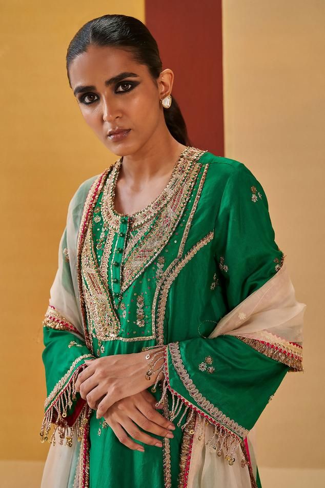 Green A-line kurta with zardozi, sequin, gota embroidered yoke in geometric pattern. Paired with pant and ivory dupatta.
Components: 3
Pattern: Embroidery
Type Of Work: Zardozi, sequin, gota, geometric
Neckline: Round
Sleeve Type: Bell sleeves
Fabric: Silk Organza
Color: Green
Other Details: 
Contrast sheer dupatta
Front embellished buttons
Tassel fringe border
Embroidery on pan hem
Occasion: Sangeet - Aza Fashions Festive Kurta With Dabka Work For Reception, Bollywood Style Zari Work Kurta For Reception, Traditional Wear Straight Kurta With Dupatta For Reception, Festive Raw Silk Kurta For Reception, Festive Kurta With Dupatta For Reception, Traditional Wear With Dupatta For Reception, Straight Kurta, Navratri Reception Palazzo Set With Gota Work, Festive Dola Silk Kurta For Reception, Transitional Season Reception Kurta In Chinon