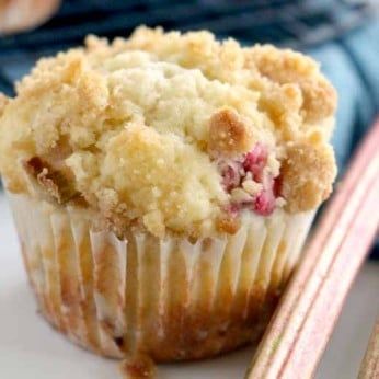 a muffin sitting on top of a white plate next to two pink chopsticks