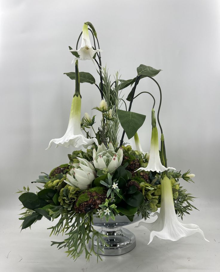 a vase filled with white flowers and greenery