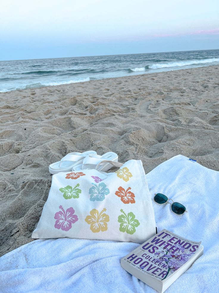 a book and sunglasses on a towel at the beach