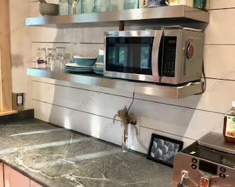 a stainless steel microwave oven sitting on top of a counter next to a toaster oven