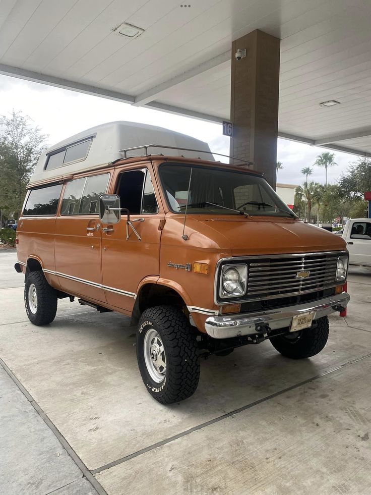 an orange van parked in front of a gas station