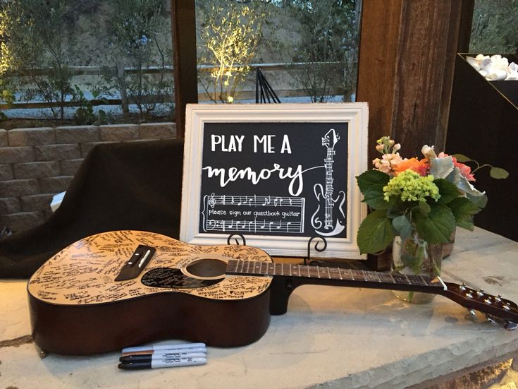 a wooden guitar sitting on top of a counter next to a sign that says play me a memory