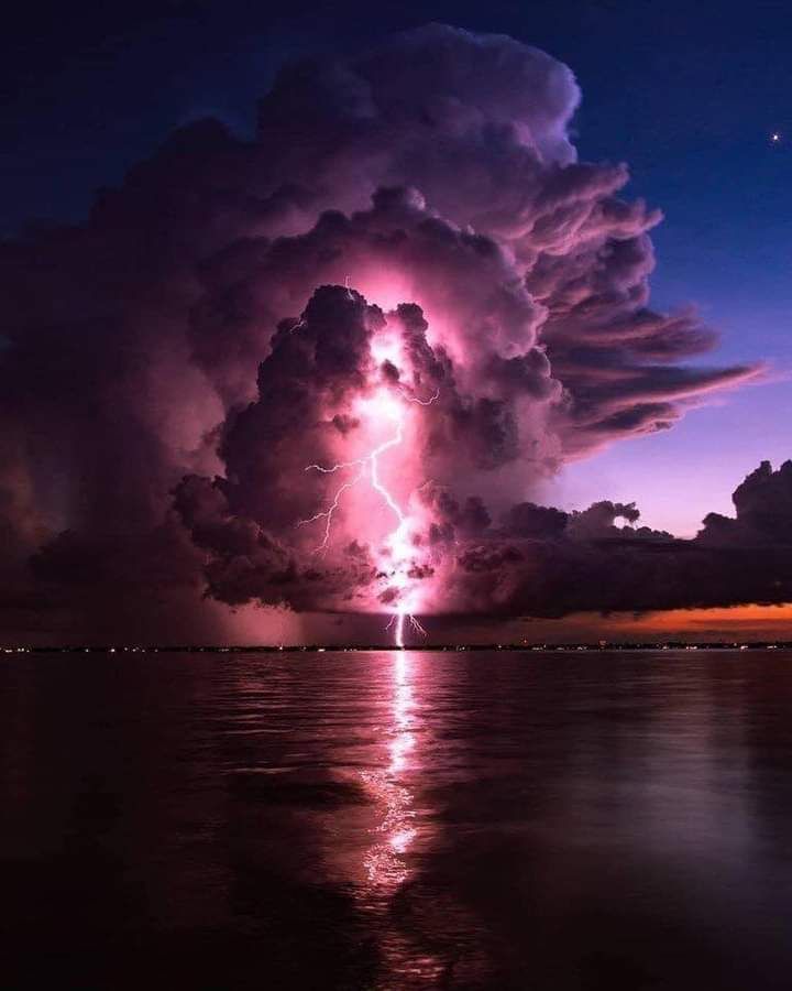 a large cloud filled with lots of purple and pink lightnings in the night sky