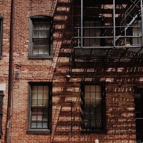 a red fire hydrant sitting in front of a tall brick building with scaffolding on it