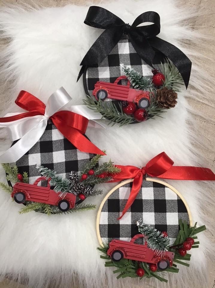 three christmas ornaments with red trucks and pine cones on them sitting on a fur rug