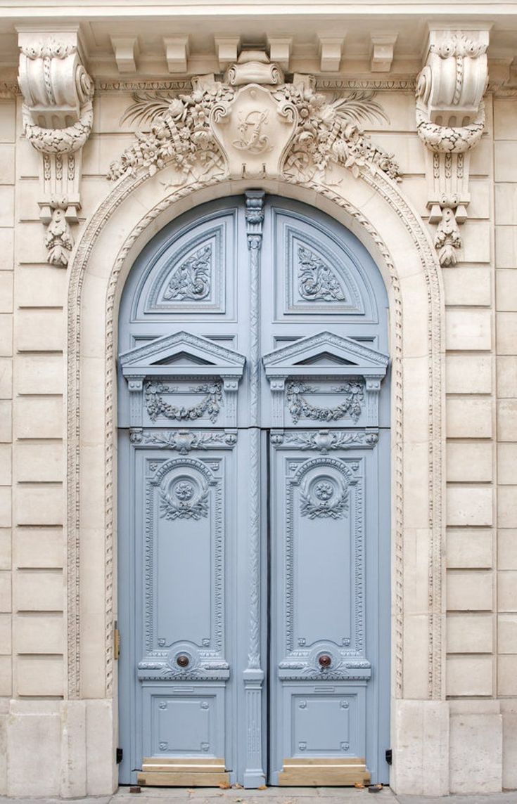 two blue doors are open in front of a stone building with ornate carvings on it