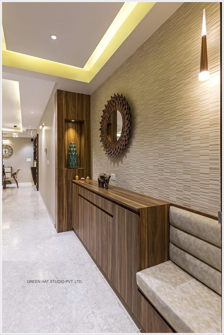 a long wooden bench sitting in the middle of a room next to a wall mounted mirror