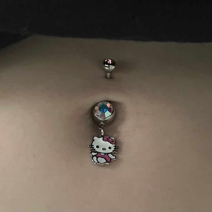 a hello kitty belly button with two charms