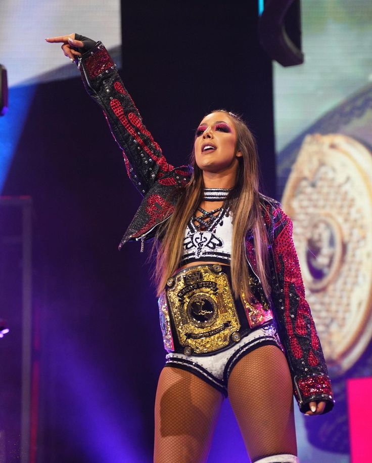 an image of a woman that is on stage with her arms in the air and one hand up