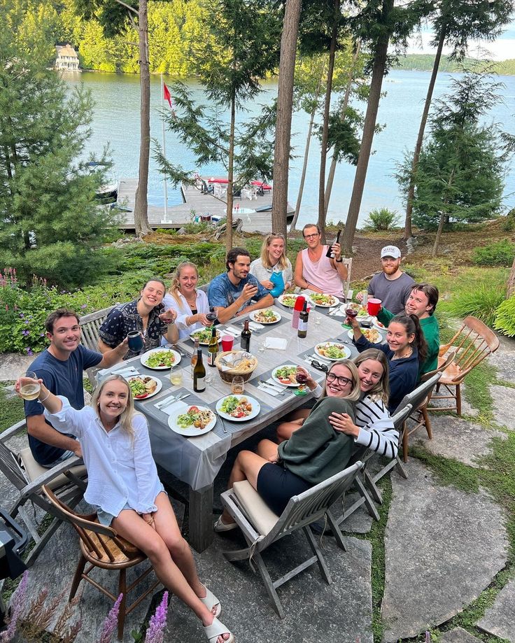 a group of people sitting around a table with plates of food and drinks on it