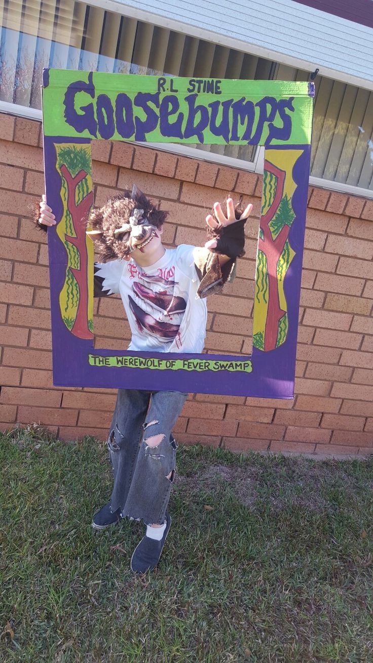 a young person holding up a poster in front of a brick wall with the words goosebomps on it