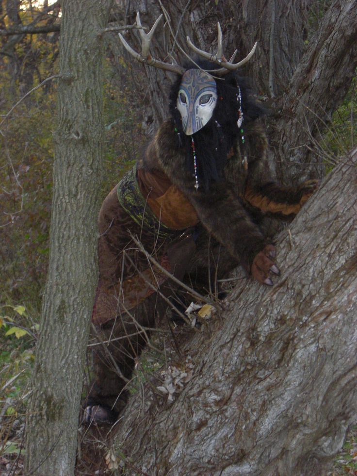 a man with an animal mask climbing up a tree