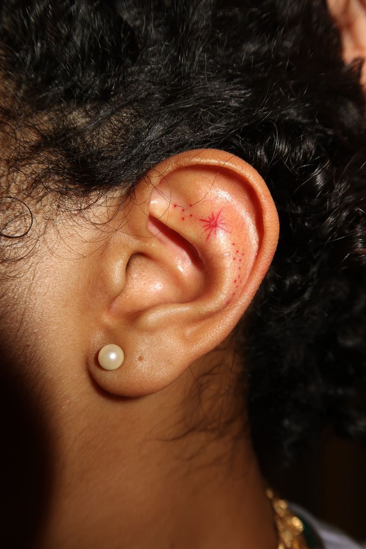 a close up of a person's ear with a small red star on it