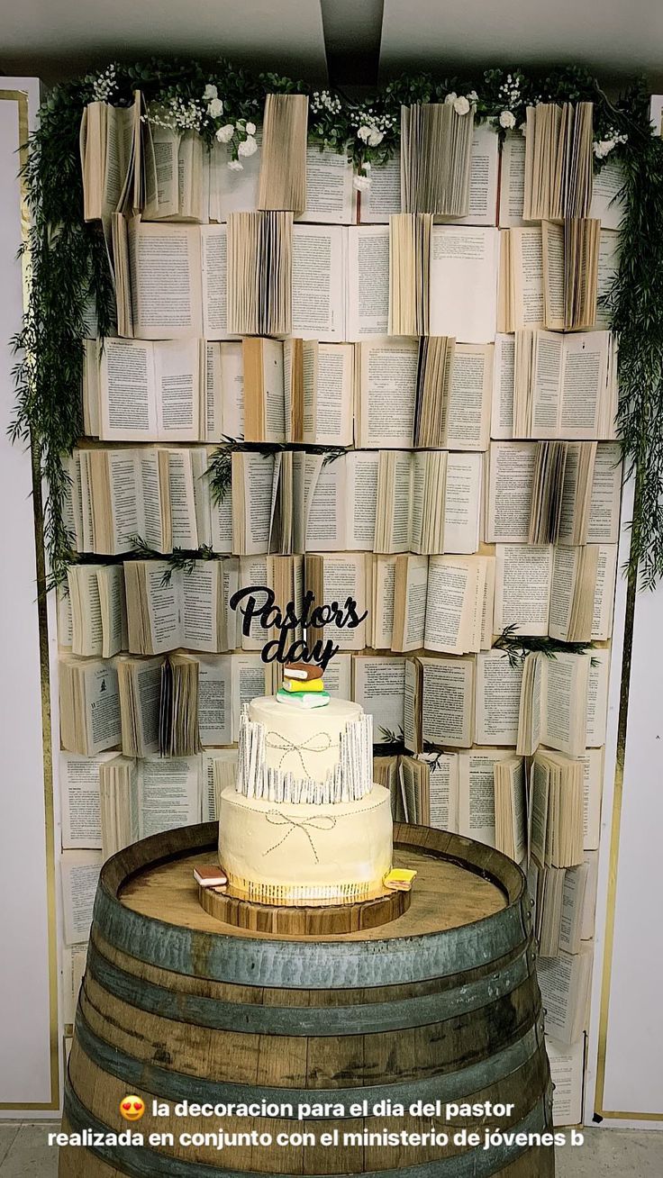 a cake sitting on top of a wooden barrel next to a wall covered in books