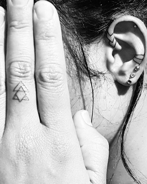 a woman with two piercings on her ears and one behind her ear is holding her hand up to her ear