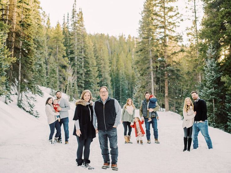 a group of people standing on top of a snow covered slope next to pine trees