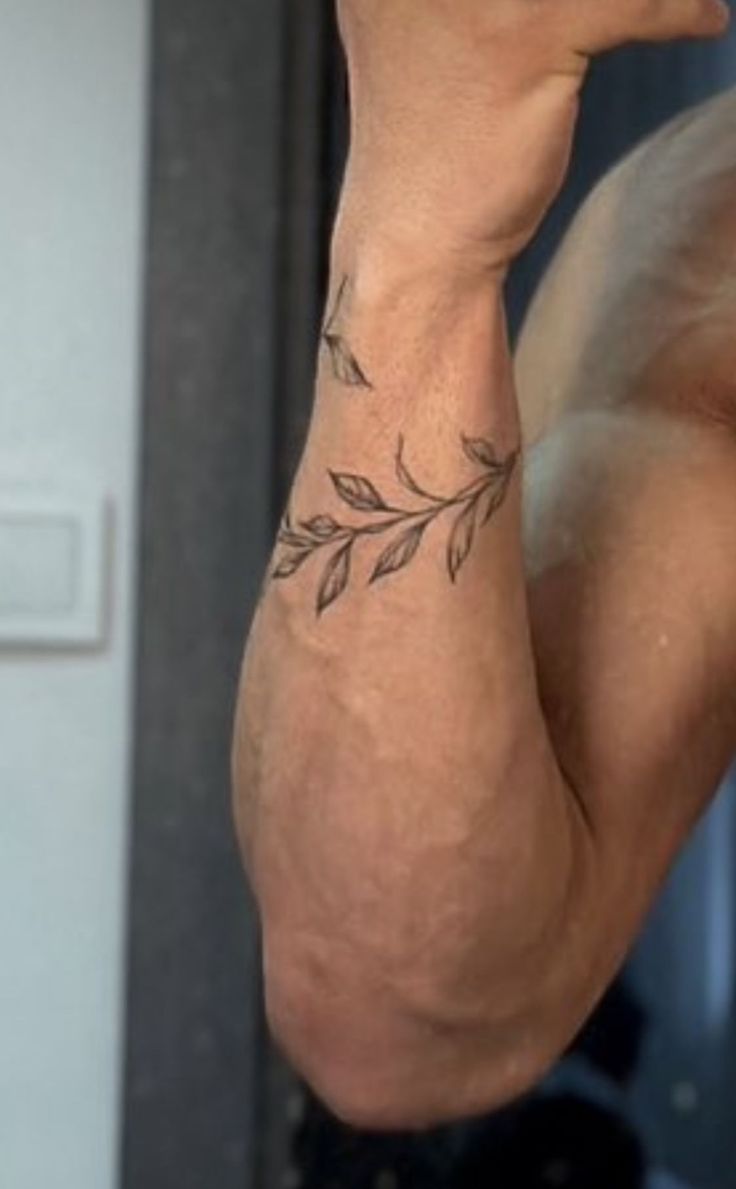 a man's arm with a leaf tattoo on it