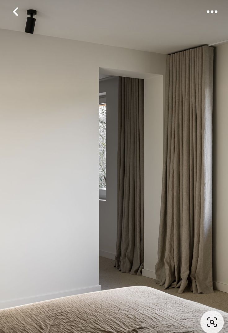 a bed sitting in a bedroom next to two tall curtains