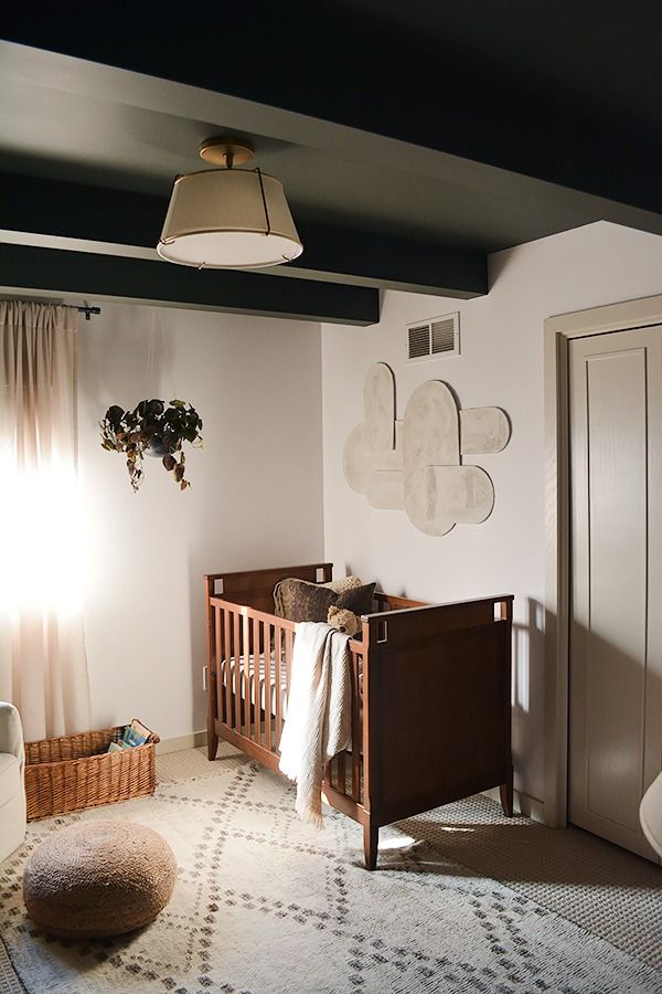 a baby's room with a crib, rug and hanging light fixture in the corner