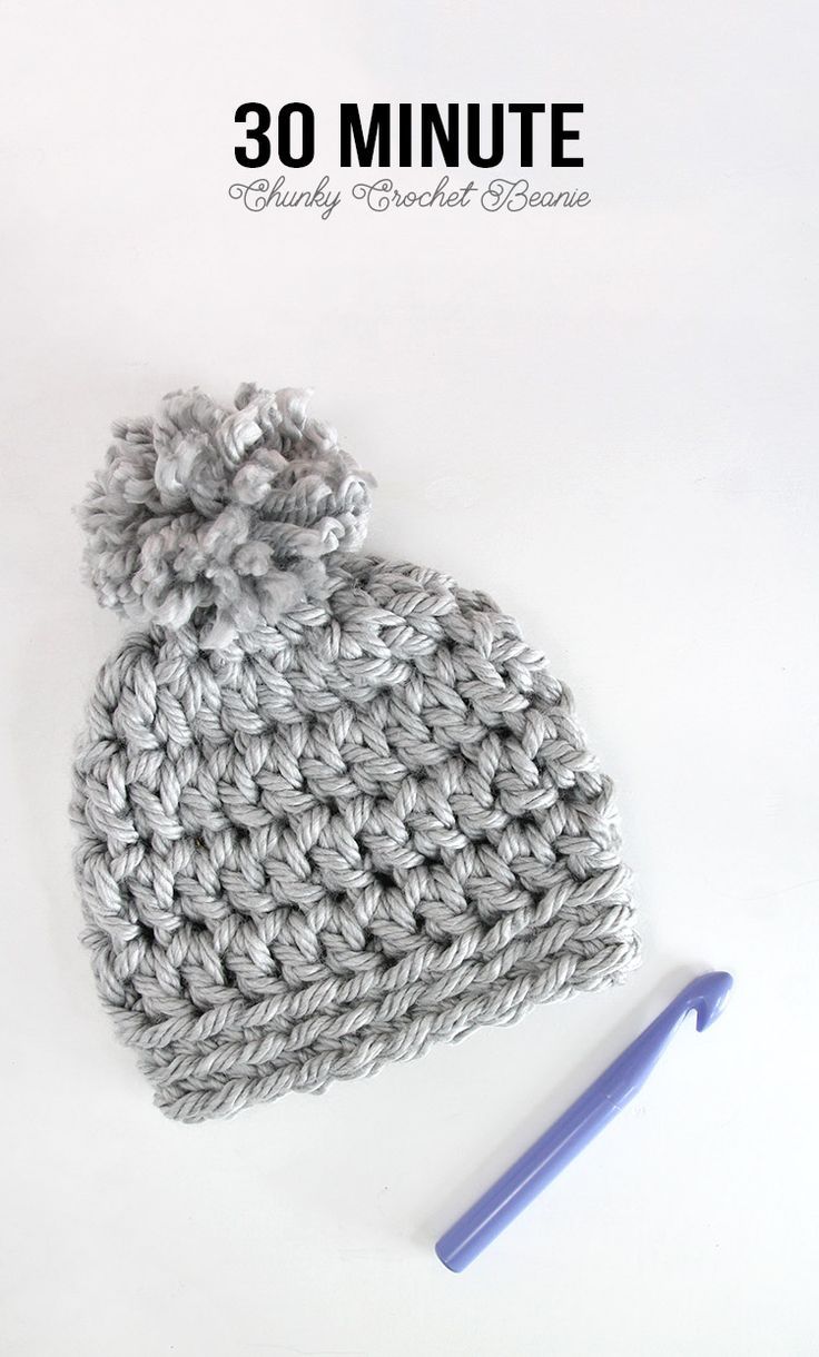 a crocheted beanie with a knitting needle next to it on a white surface