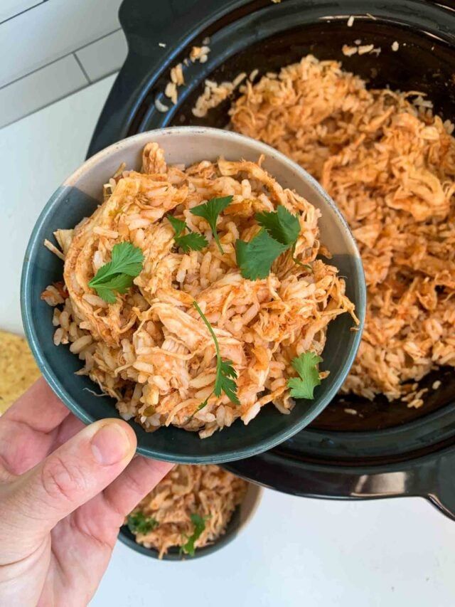 someone is holding a small bowl full of rice and garnished with cilantro