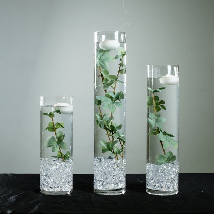 three glass vases with plants in them on a black countertop next to each other