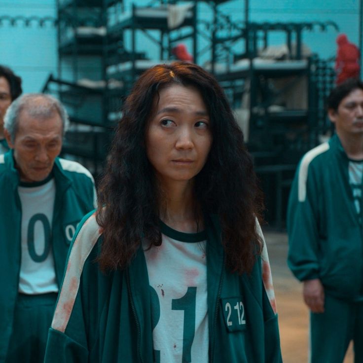 a group of people standing around each other in green outfits and numbers on their shirts