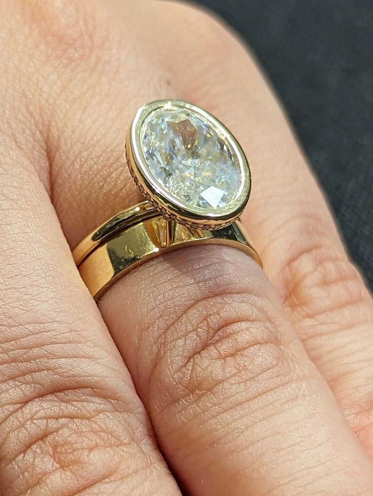 a close up of a person's hand holding a ring with a diamond on it