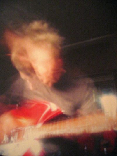 blurry photograph of a man playing an electric guitar