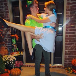 a man holding a woman in his arms while standing next to a door with pumpkins