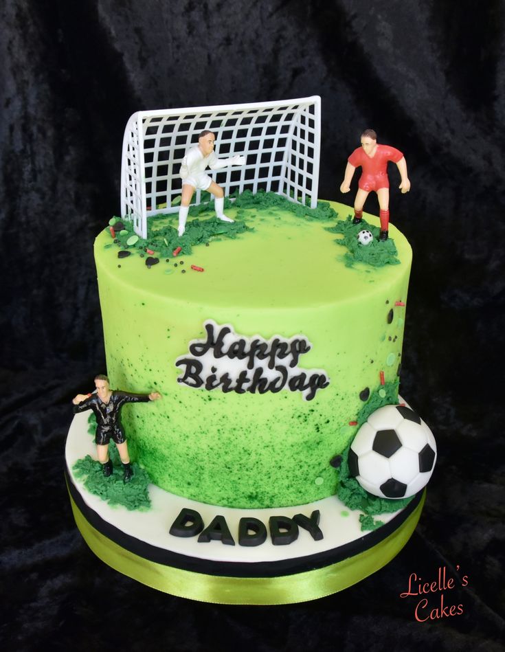 a soccer themed birthday cake with two people on top and a goalie in the background