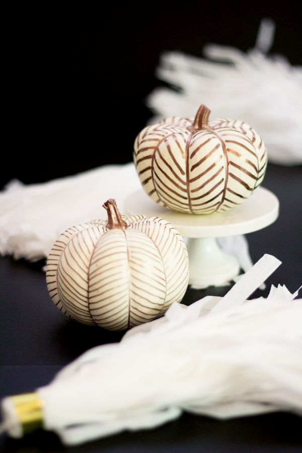 two white pumpkins sitting on top of a cake plate next to some tissue paper