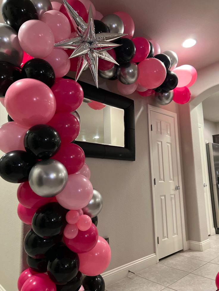 the balloon arch is decorated with black, pink and silver balloons for a star themed birthday party