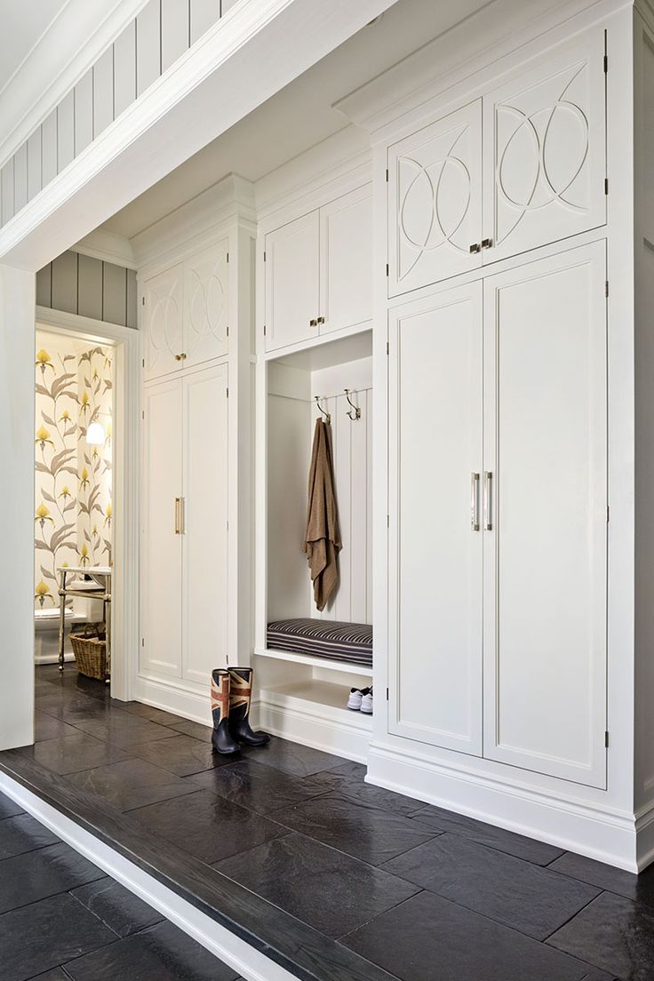 an entryway with white cabinets and black flooring