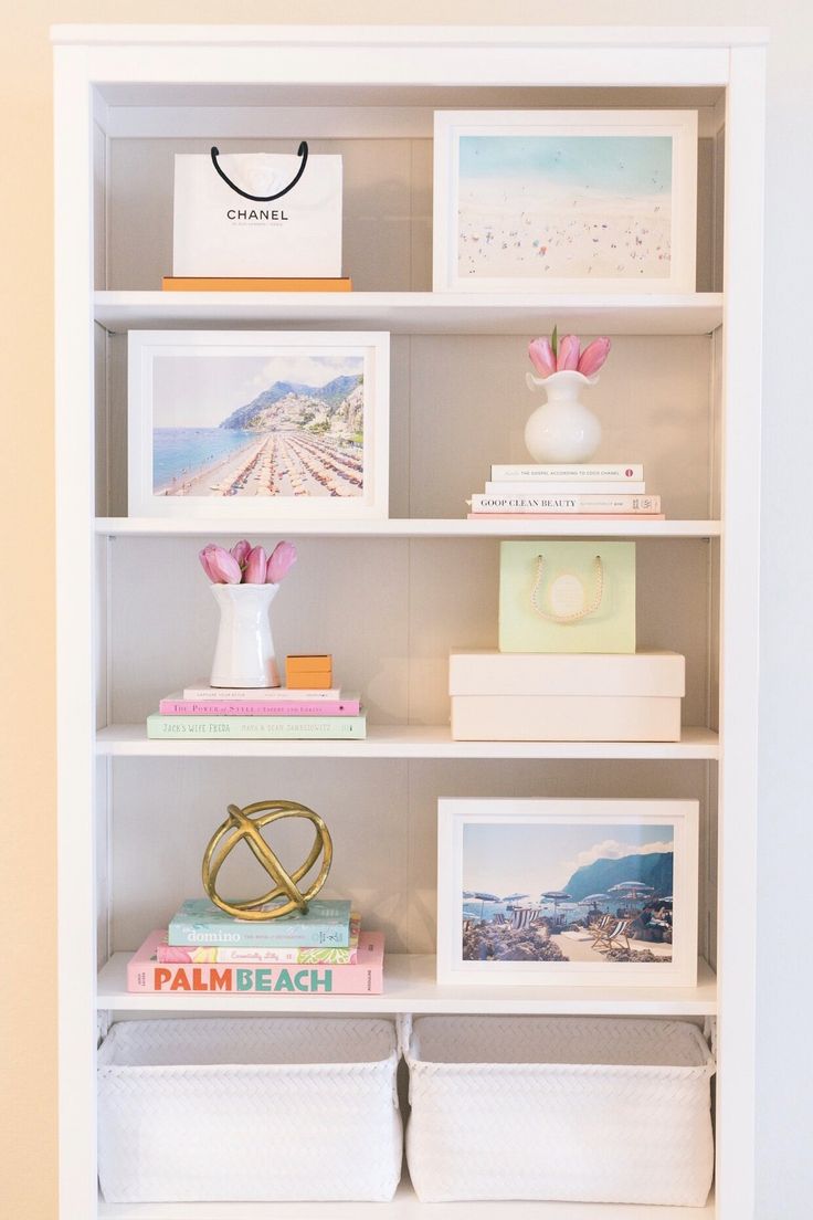 a white book shelf filled with pictures and other items on top of eachother