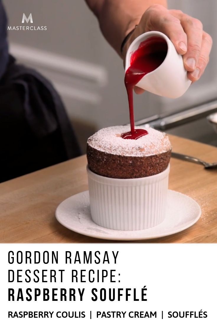 a person pours red sauce on top of a dessert with raspberry souffle