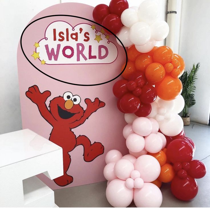 the balloon arch has an elmo character on it and is next to some balloons