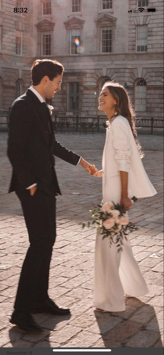 a man and woman holding hands in front of a building