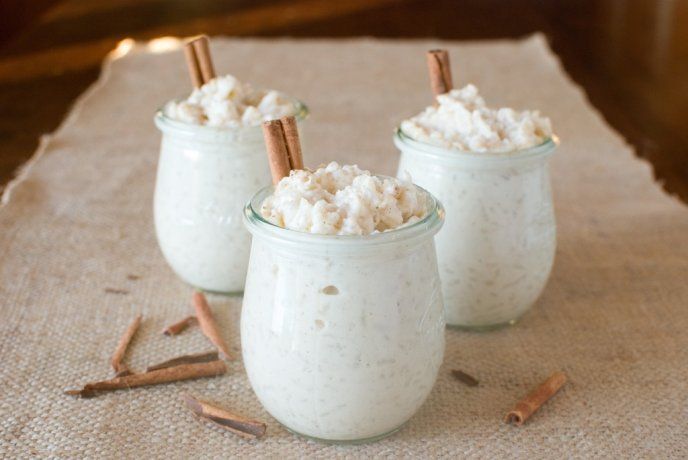 three glasses filled with marshmallows and cinnamon sticks on a linen tablecloth