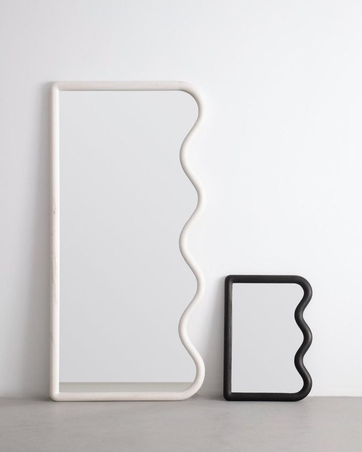 a white shelf sitting next to a black object on top of a table in front of a white wall