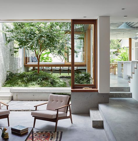 a living room with two chairs and a rug in front of the window that looks out onto an outdoor courtyard