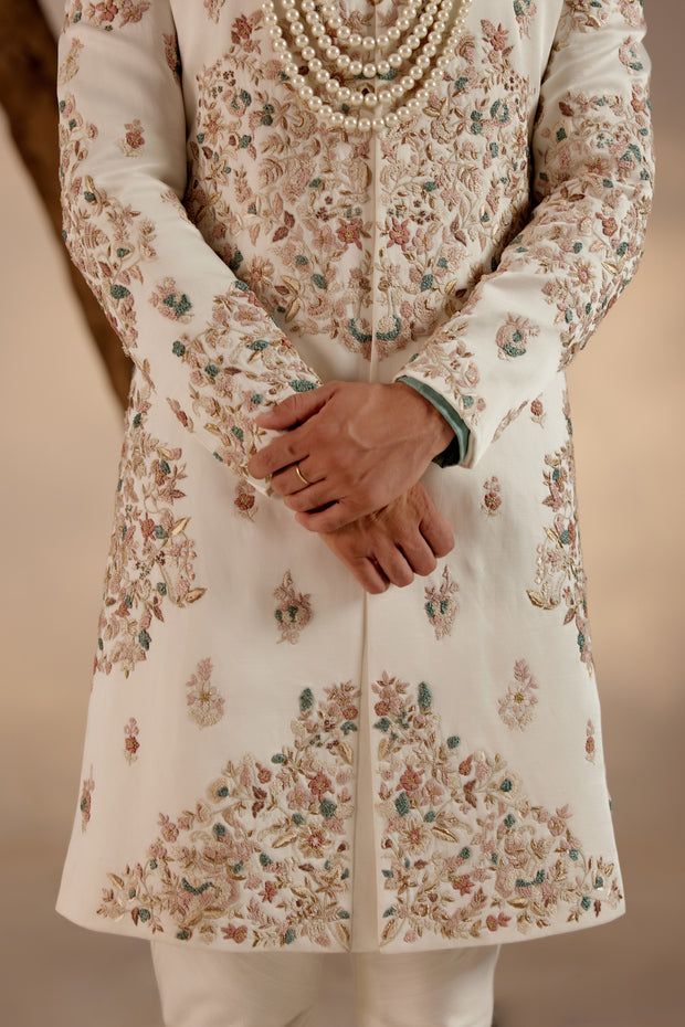 Opaline Sherwani Set | Jatin Malik Introducing our ivory placement hand-embroidered sherwani set, a true epitome of elegance and craftsmanship. The foundation of this ensemble is adorned with colorful resham threads, intricately woven alongside golden zari and dabka accents, creating a mesmerizing visual composition. Paired with a hand-embroidered chateau grey stole and safa, this ensemble exudes sophistication and style. Perfect for those seeking to make a statement with their attire, this sherwani set beautifully combines tradition with contemporary flair, making it ideal for special occasions and celebrations. Included in purchase: Sherwani, Kurta, Churidar, Stole, Safa Product Specification Color: Ivory Fabric: Linen silk Occasion: Engagement, Wedding, Bridal, Reception Style: Sherwani Sherwani Hand Work Design, Ivory Sherwani, Jatin Malik, Mansions Interior, Sherwani For Men Wedding, Embroidered Sherwani, Luxury Mansions, Blouse Yoke, Wedding Dresses Men Indian