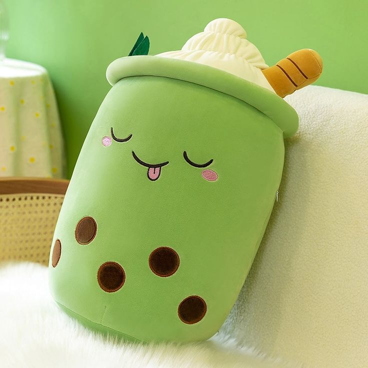 a green stuffed animal sitting on top of a white couch