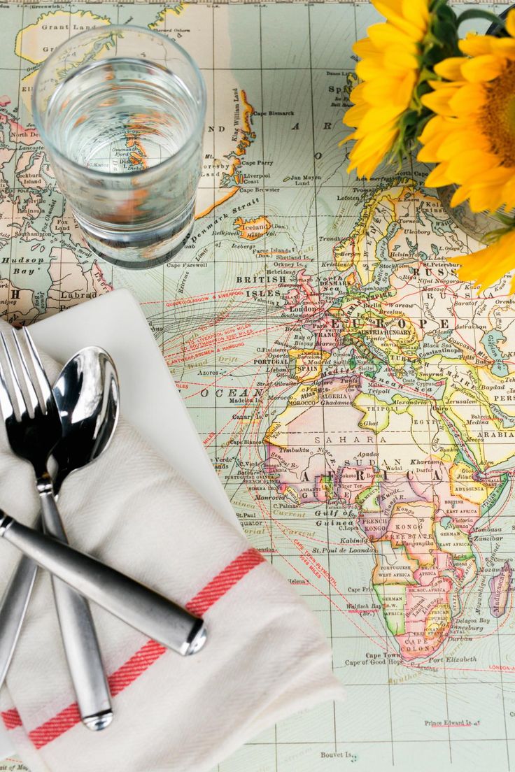 a place setting with sunflowers and silverware on a world map table cloth