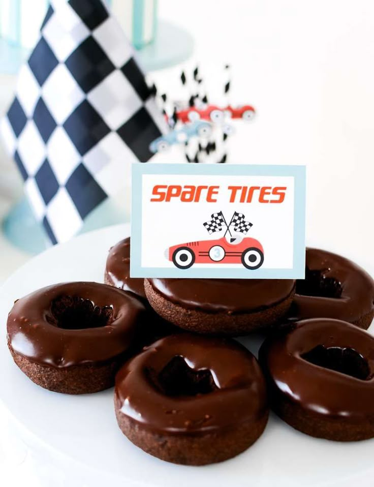 chocolate covered donuts sitting on top of a white plate with a sign that says spare tires