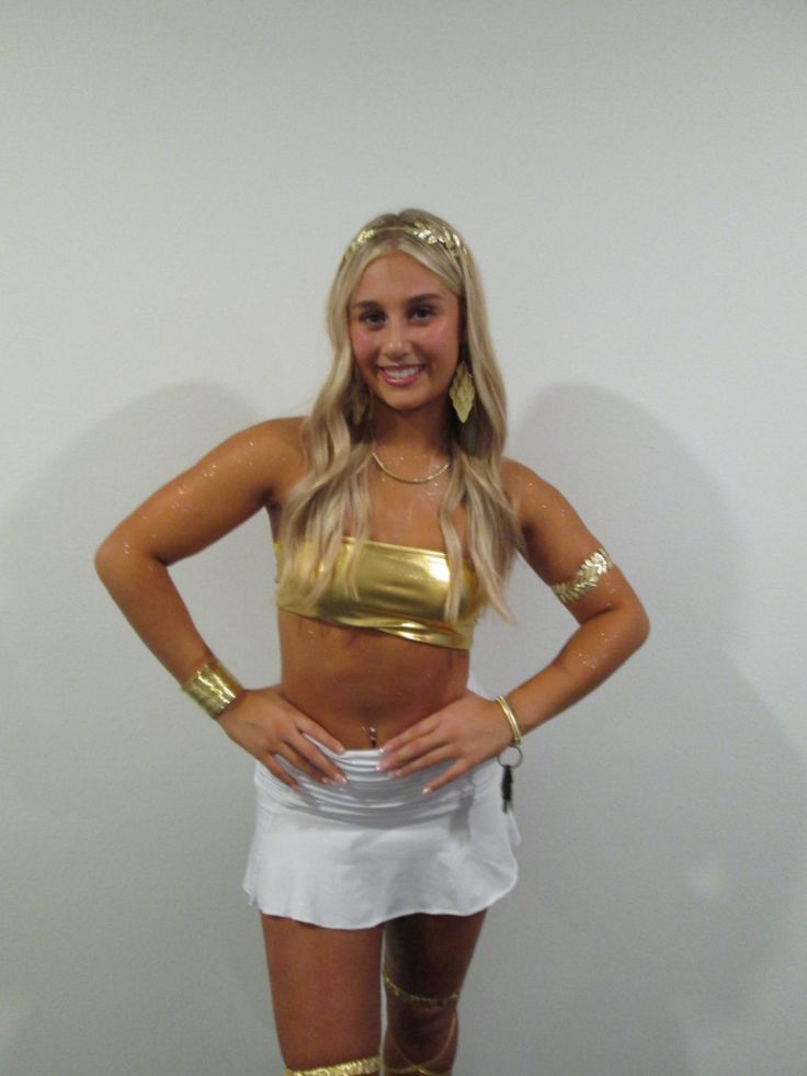 a woman dressed in gold and white posing for the camera with her hands on her hips